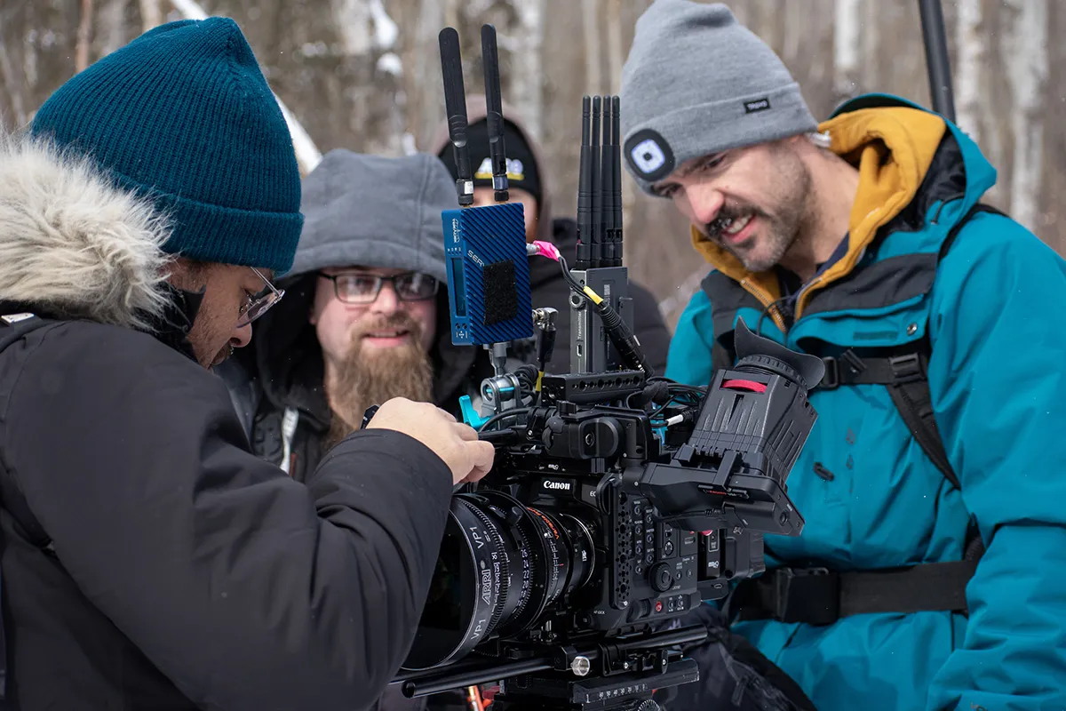 Several people look at a movie camera.