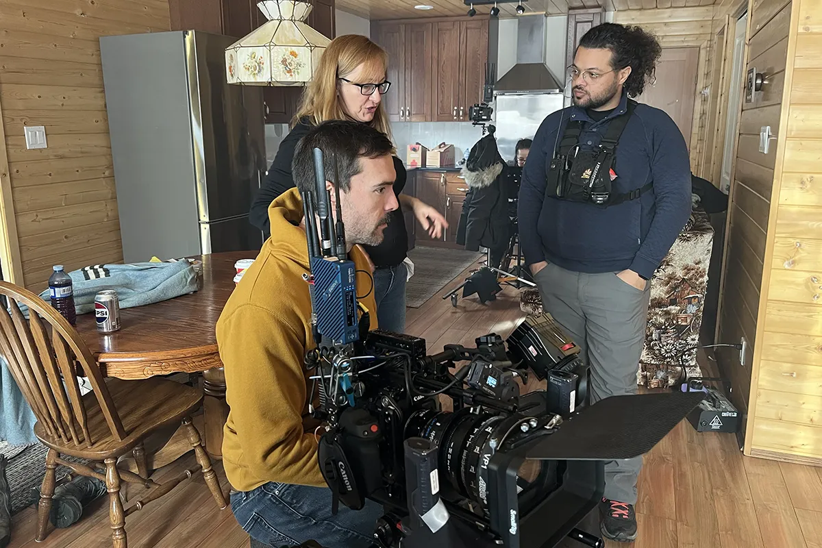 Several people with movie equipment having a discussion in a kitchen.